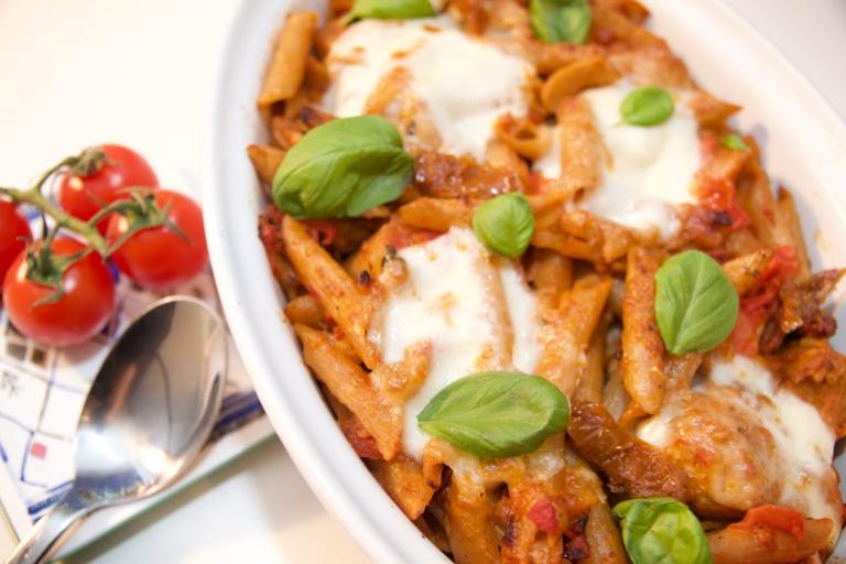 Cheesy pasta dish with vegetarian sausages and topped with mozzarella cheese and basil
